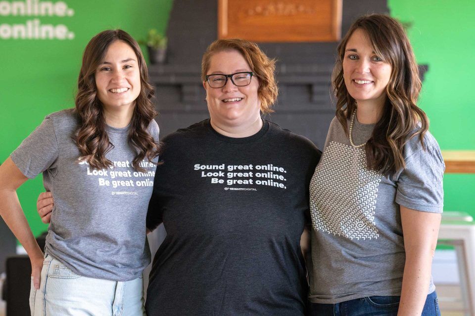 Three people in grey 1Eighty Digital t-shirts, all smiling.