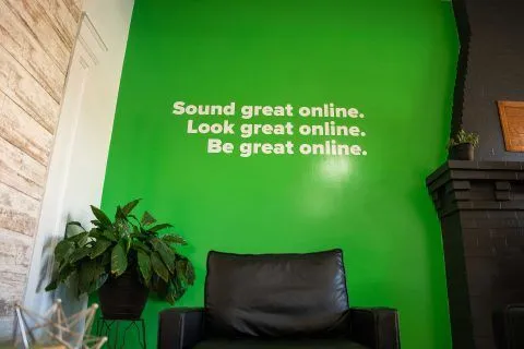1Eighty Digital slogan on green wall with black leather chairs in modern office.