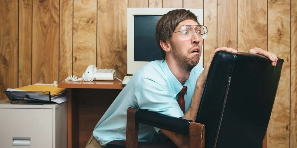 Person hiding behind an office chair in a retro-style AI marketing office.