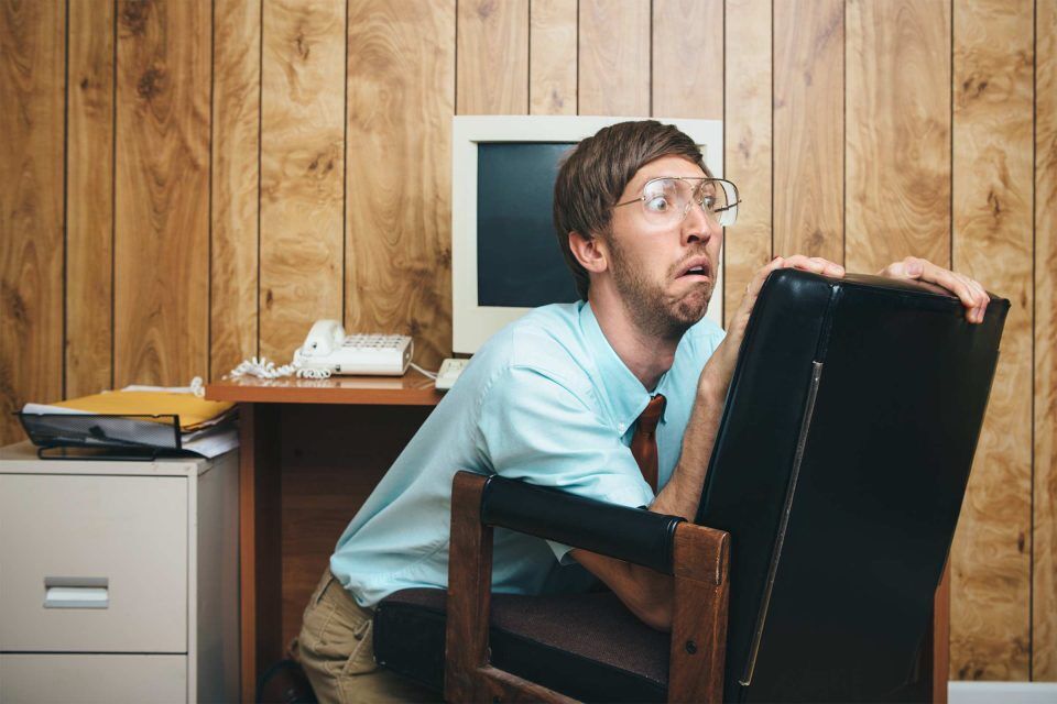 Person hiding behind an office chair in a retro-style AI marketing office.