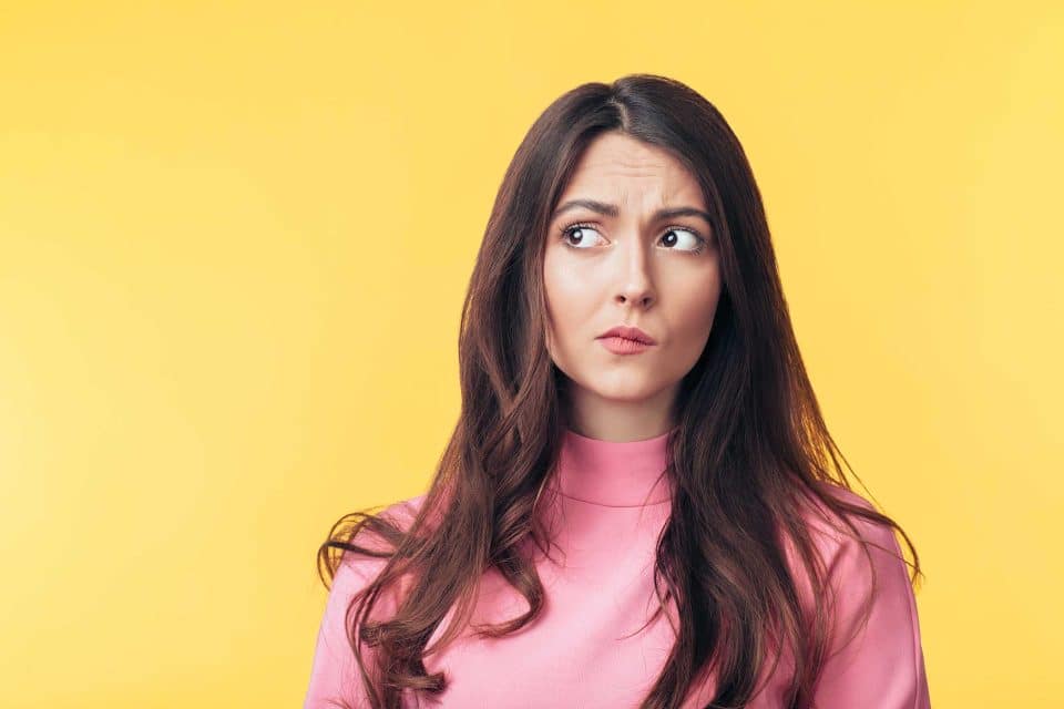 Woman in a pink shirt glances sideways amid rebranding, yellow backdrop.