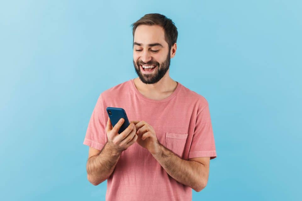 Smiling man in a pink shirt enjoys his customer journey on a smartphone.