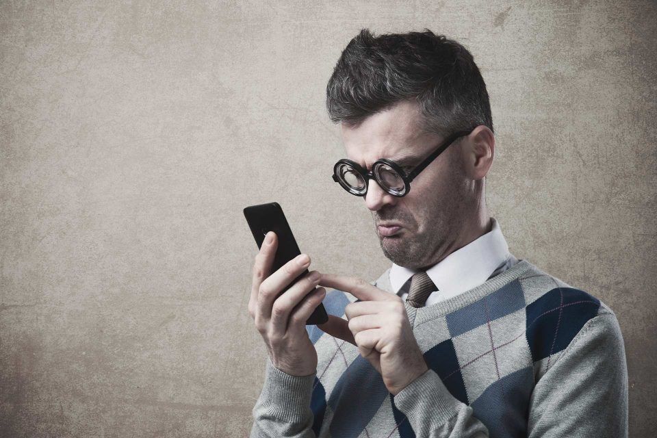 Man wearing glasses frowning at his Google Business Profile on his smartphone.