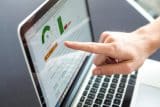 Hand pointing at laptop screen showing SEO data with charts and graphs.