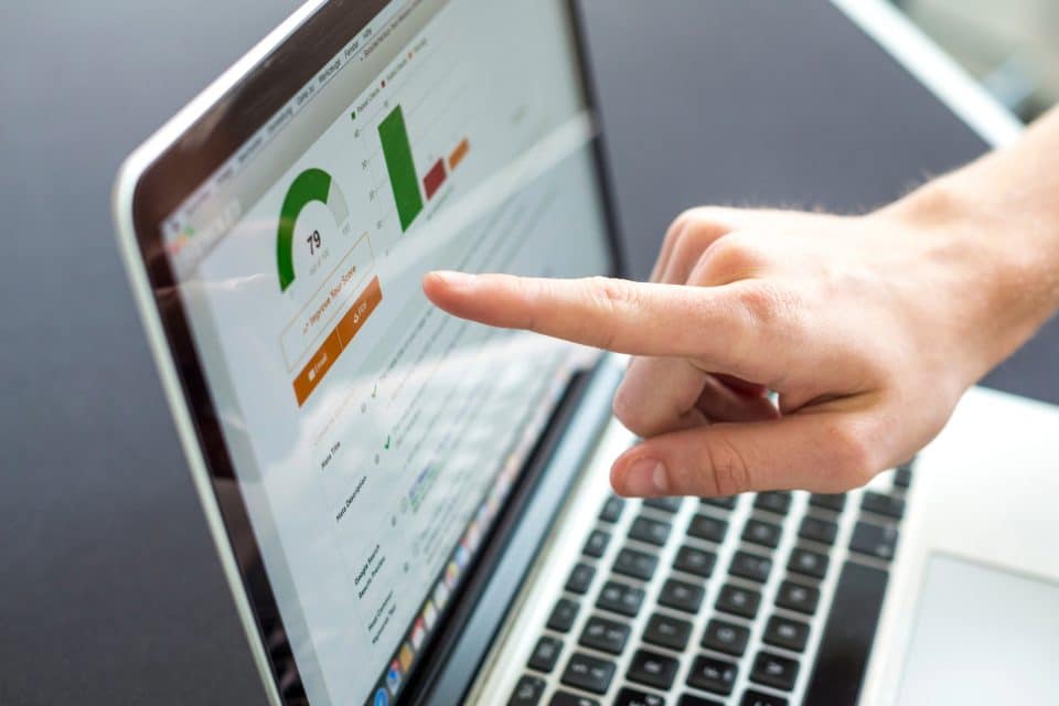 Hand pointing at laptop screen showing SEO data with charts and graphs.
