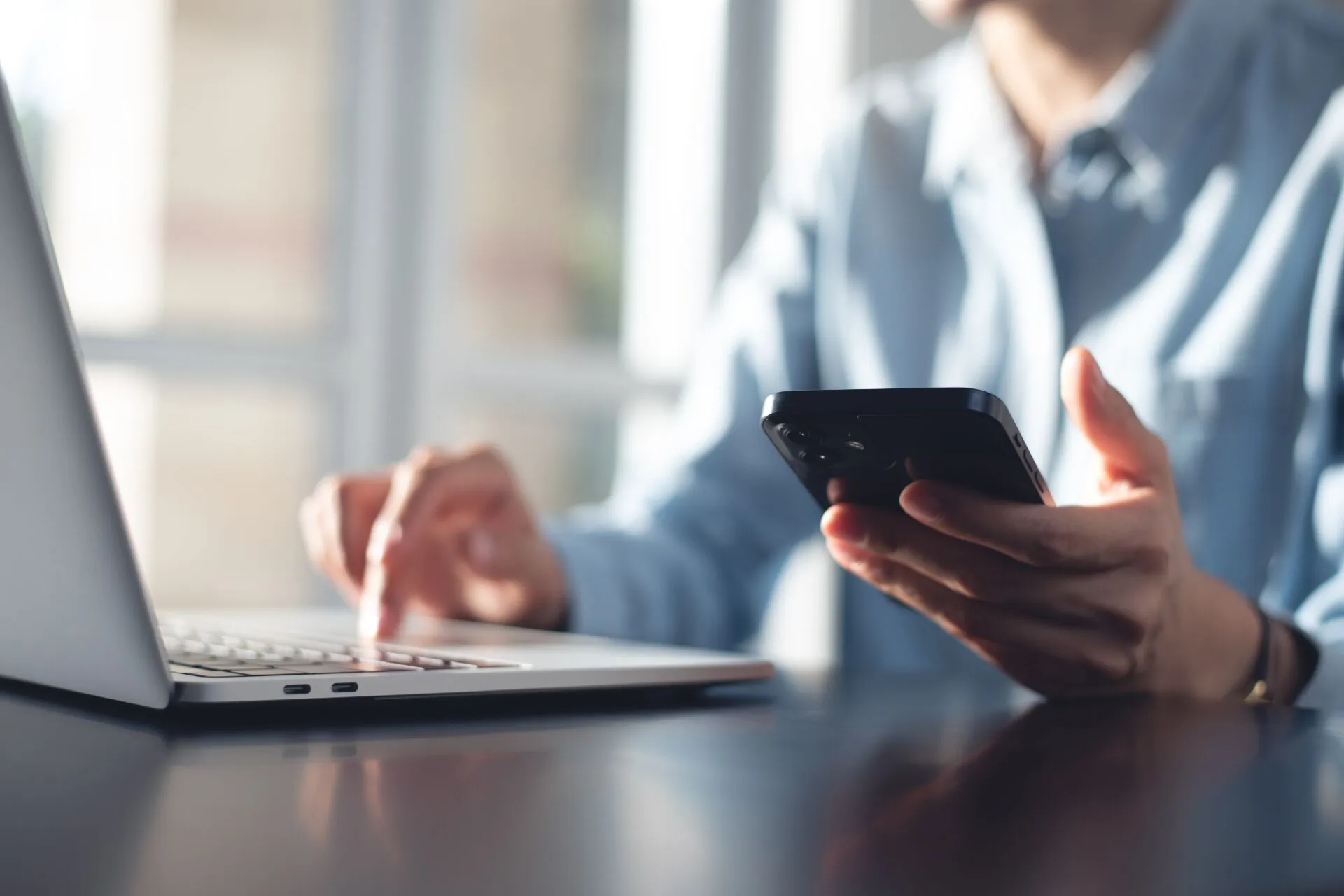 Person using a laptop and smartphone to manage internal linking for SEO.