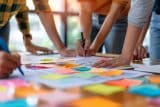 People collaborating at a table with colorful sticky notes and papers.