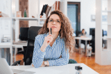 Striped-shirt person pondering email re-engagement strategy at their desk.