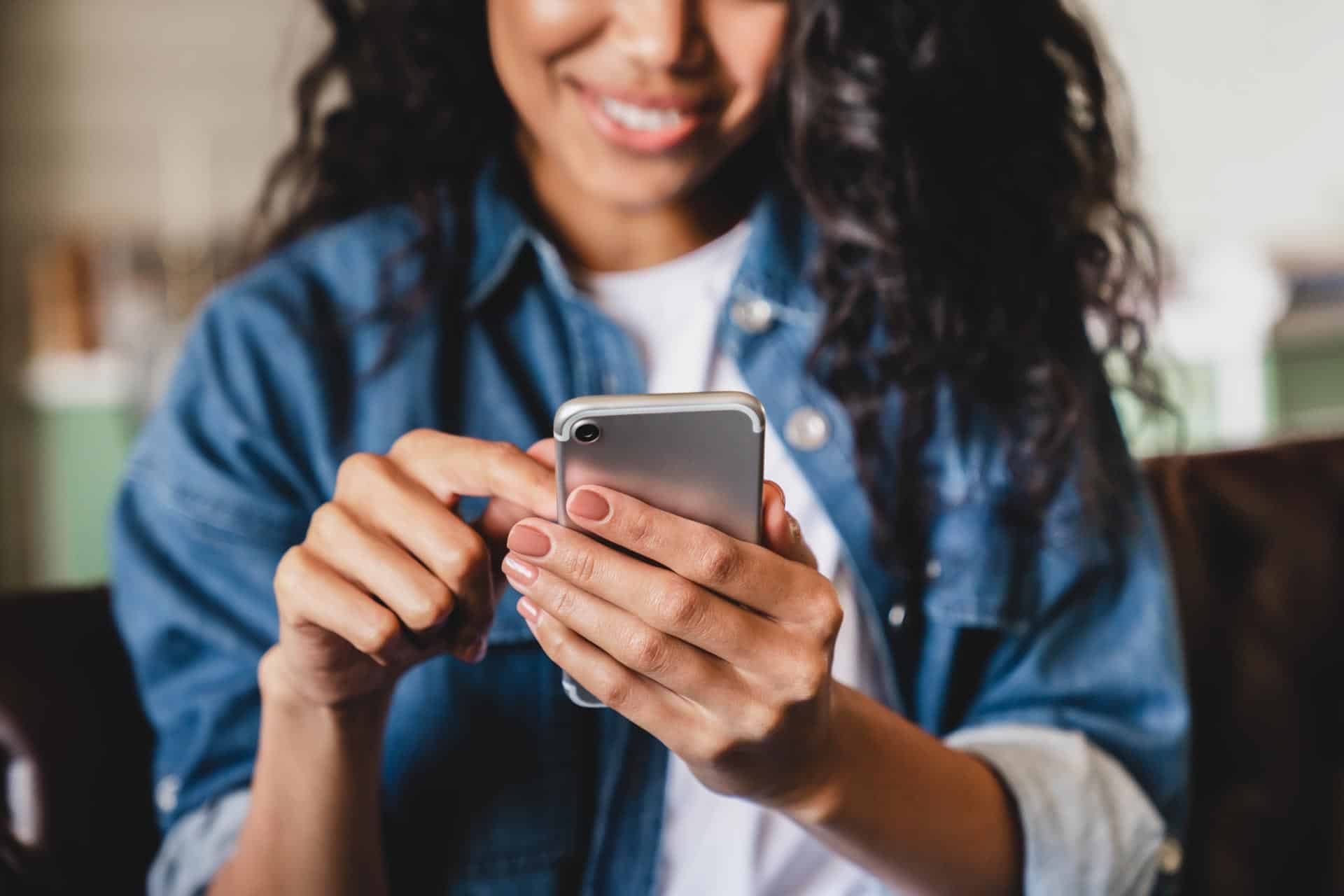 A woman smiles while using a smartphone for a marketing audit.