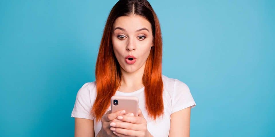 Woman in white shirt looks surprised by a context marketing message on her smartphone.