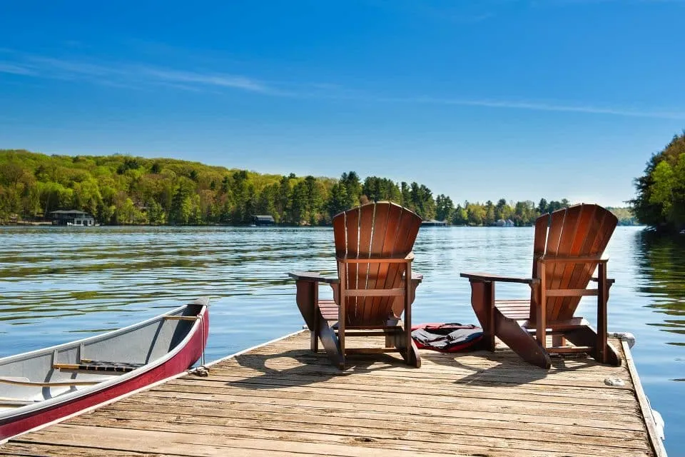Two wooden chairs on a dock in Kosciusko County, overlooking a calm lake.