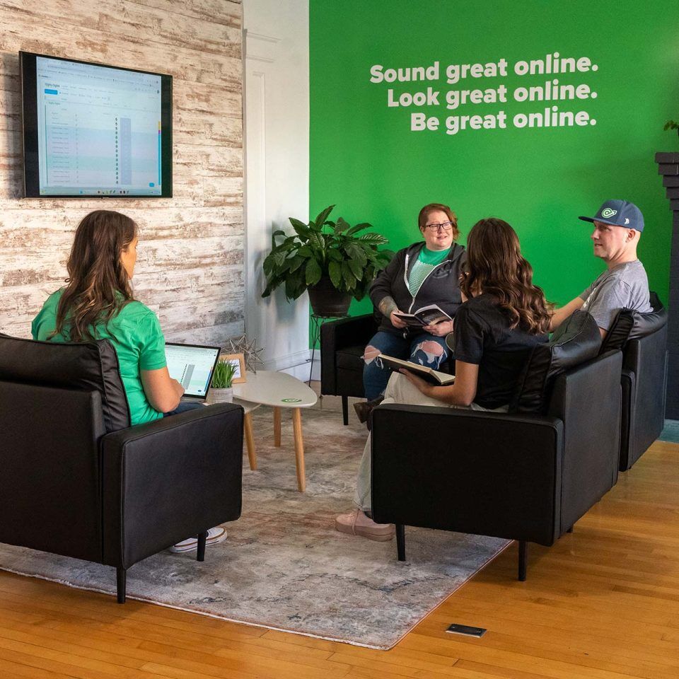 Four people sitting in a living room, having a casual meeting.