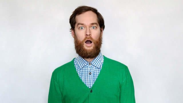 Man with beard and green sweater looking surprised.