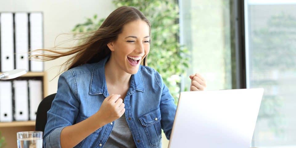 Person smiling and raising fists in excitement while reading a marketing email.