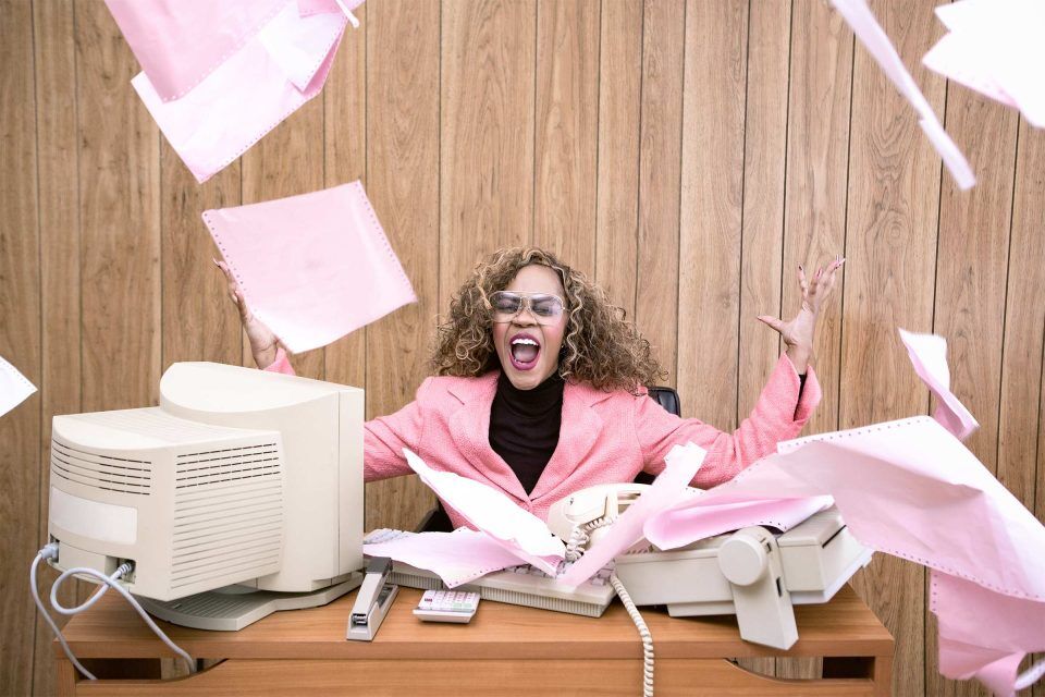 Person in retro office, excitedly tossing marketing strategy papers in the air.