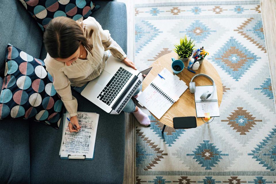 Woman working on a laptop with LinkedIn marketing notes and stationery.