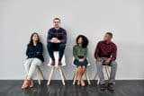 Four people seated, one perched above, exchanging social media marketing tips.