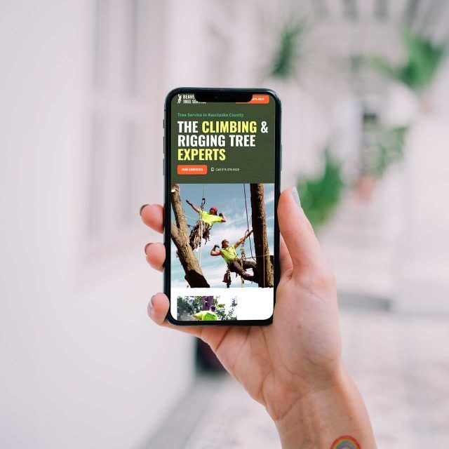 Hand displaying Beaver Dam Tree Services tree climbing website.