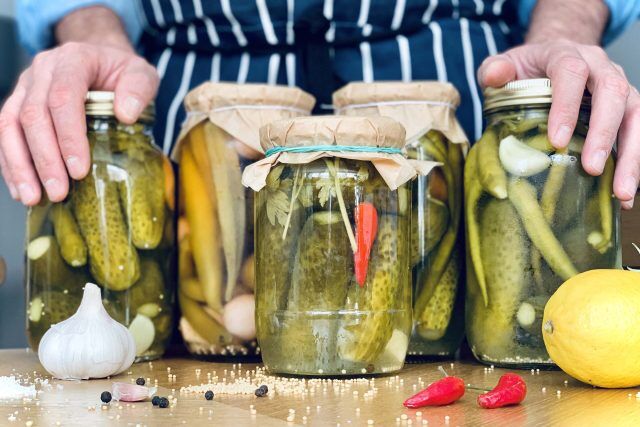 Person arranging jars of pickles for a Blue Barn fundraising event.