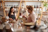 Two women discuss in a bulk store, strategizing to close more sales.