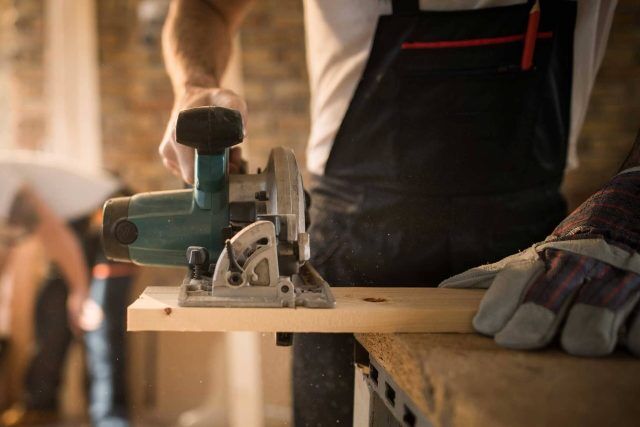 Person using a circular saw to cut a piece of wood.