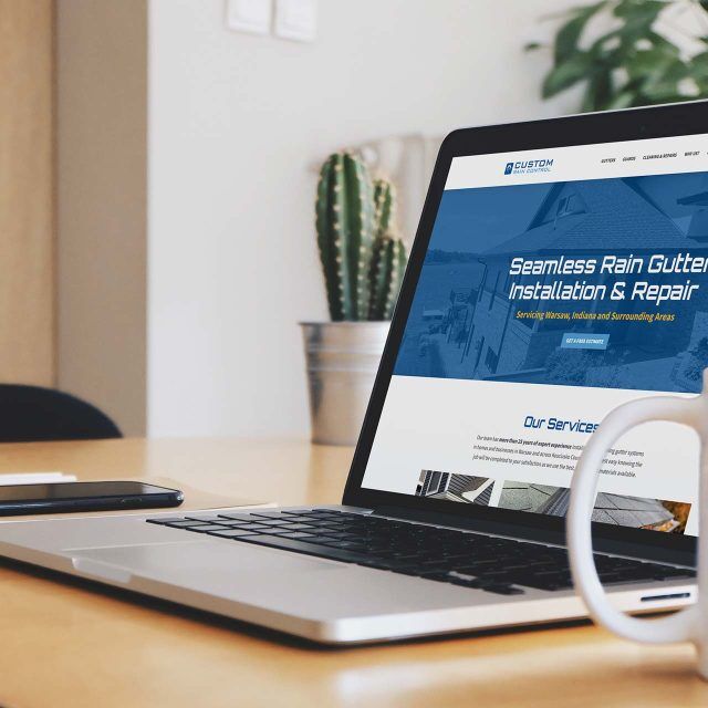 Open laptop displaying a rain gutter installation website on a desk.