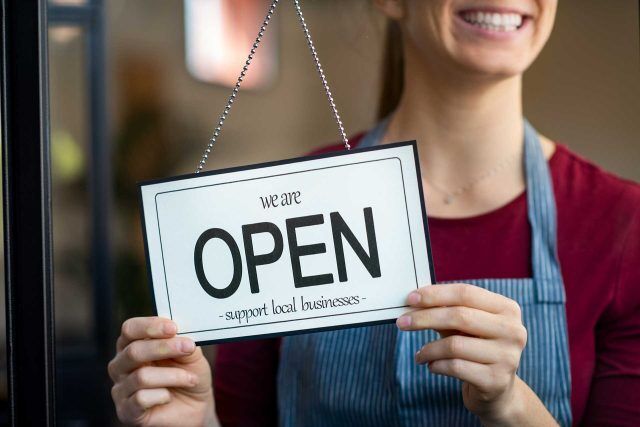A person holds a We are open sign at Huntington County Chambers store.