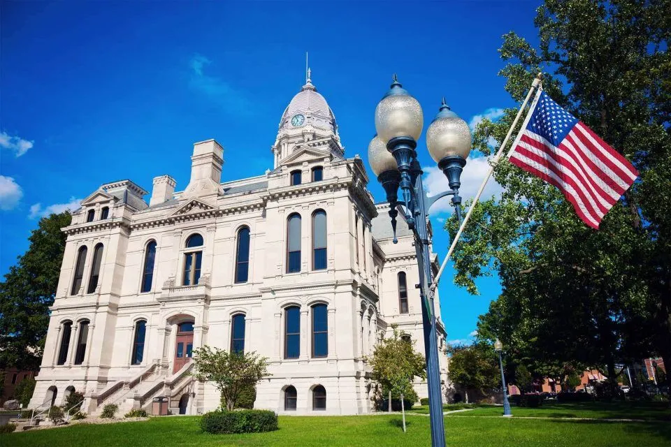 Kosciusko County courthouse, flag, and lamp post on a sunny day.