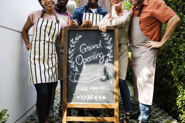 People in aprons at the EVI Training grand opening sign.