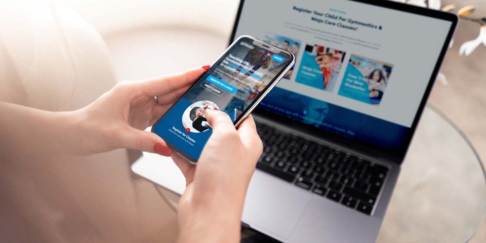 Person using a smartphone with a laptop open near Lake City Gymnastics.