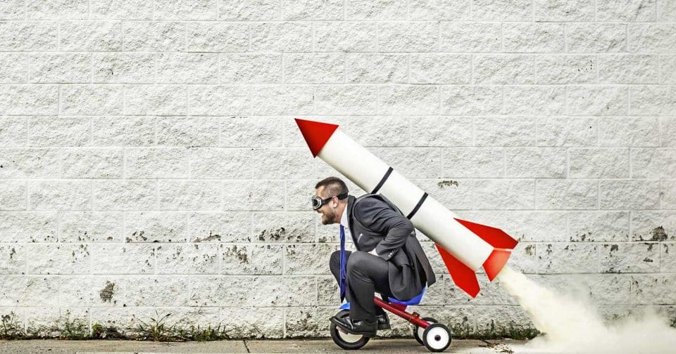Man in a suit on a tricycle, creatively marketing on a small budget.