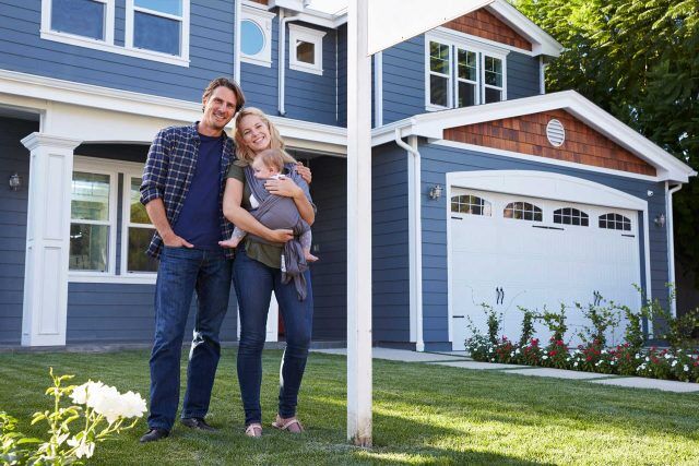 A couple with a baby beams outside their NCIAR blue house.