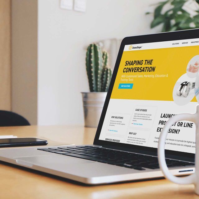 Laptop showcasing OsteoShapes website next to a steaming mug.