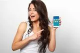 Smiling woman points at phone showcasing 5-star reviews.