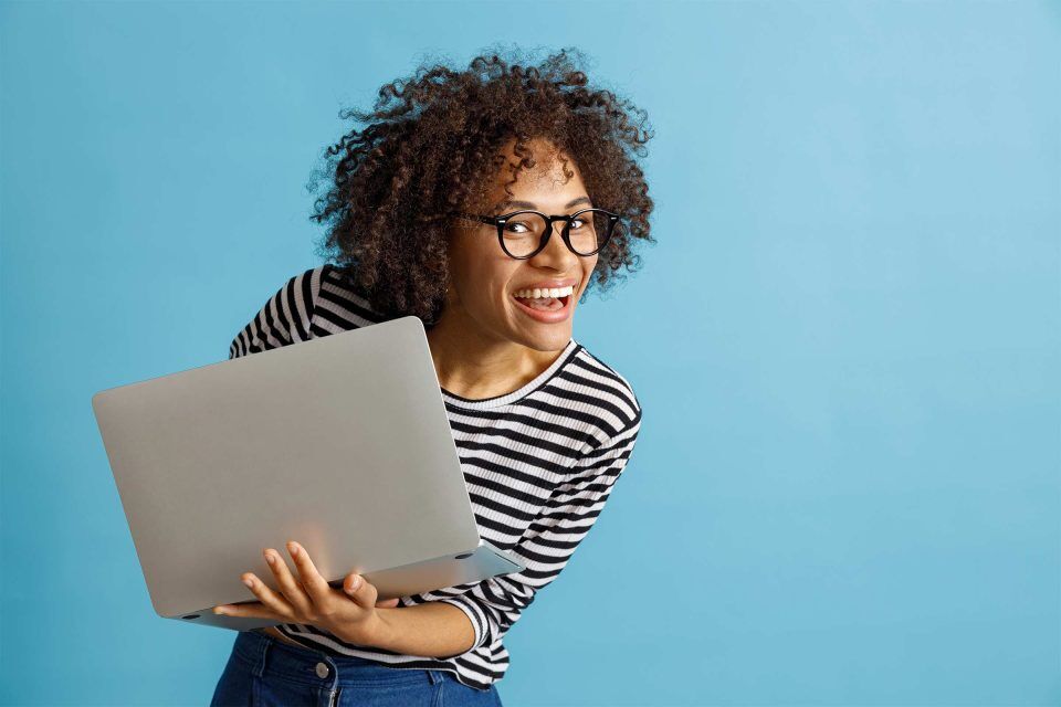 Person smiling, repurposing old blog content on a laptop against a blue background.