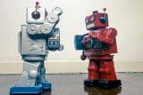 Two vintage toy robots in a standoff, like mail marketing rivals.