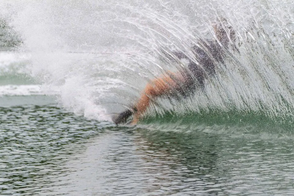Person waterskiing near Syracuse, creating a large spray of water behind them.