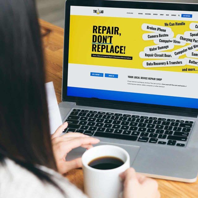 Person with coffee viewing repair shop website on a laptop.