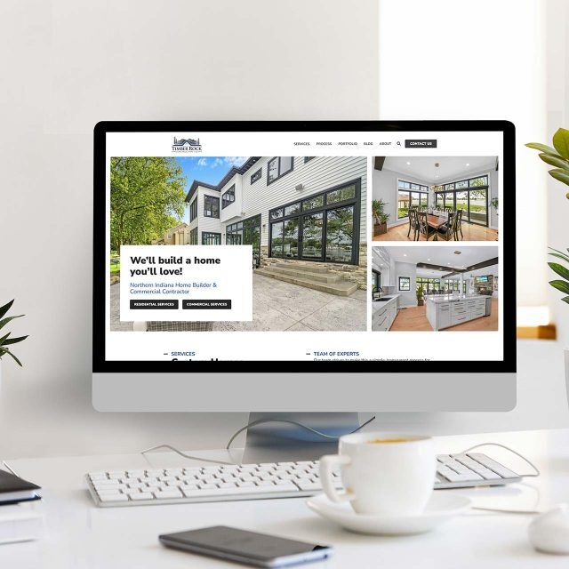 Timber-framed website on screen, plants surround the display.