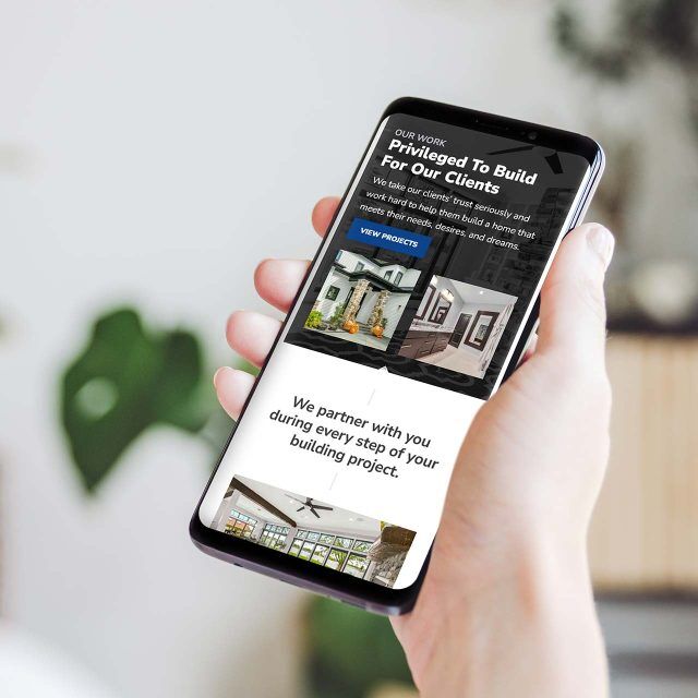 Person with a smartphone displaying Timber Rocks building design website.