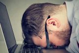 Person resting head on a laptop keyboard, exhausted from website update.