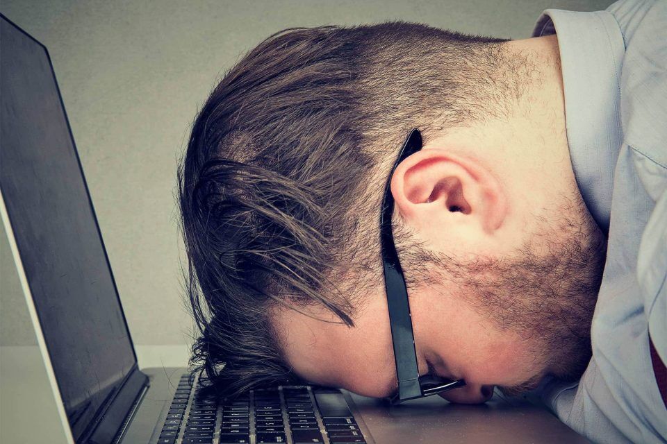Person resting head on a laptop keyboard, exhausted from website update.