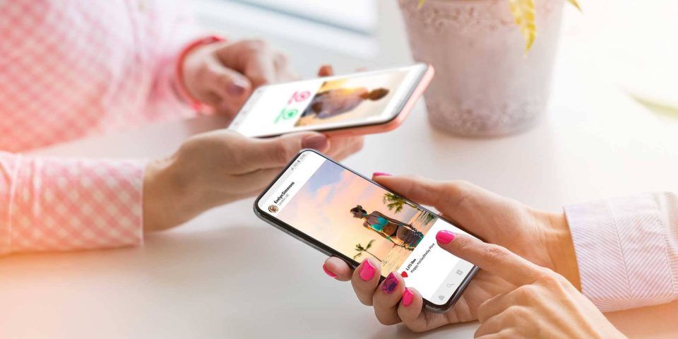 People browsing social media platform photos on smartphones at a table.
