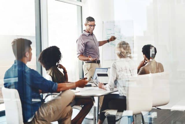 Person leading a professional development session in a meeting room with a whiteboard.