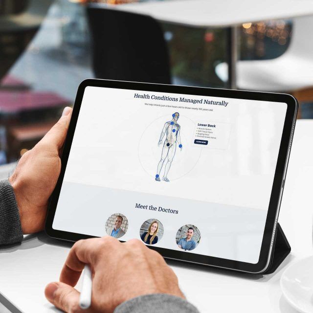 Person viewing Warsaw Chiropractic website on tablet, near a coffee cup.