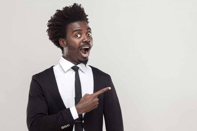 Person in suit, surprised, pointing to digital marketing services backdrop.