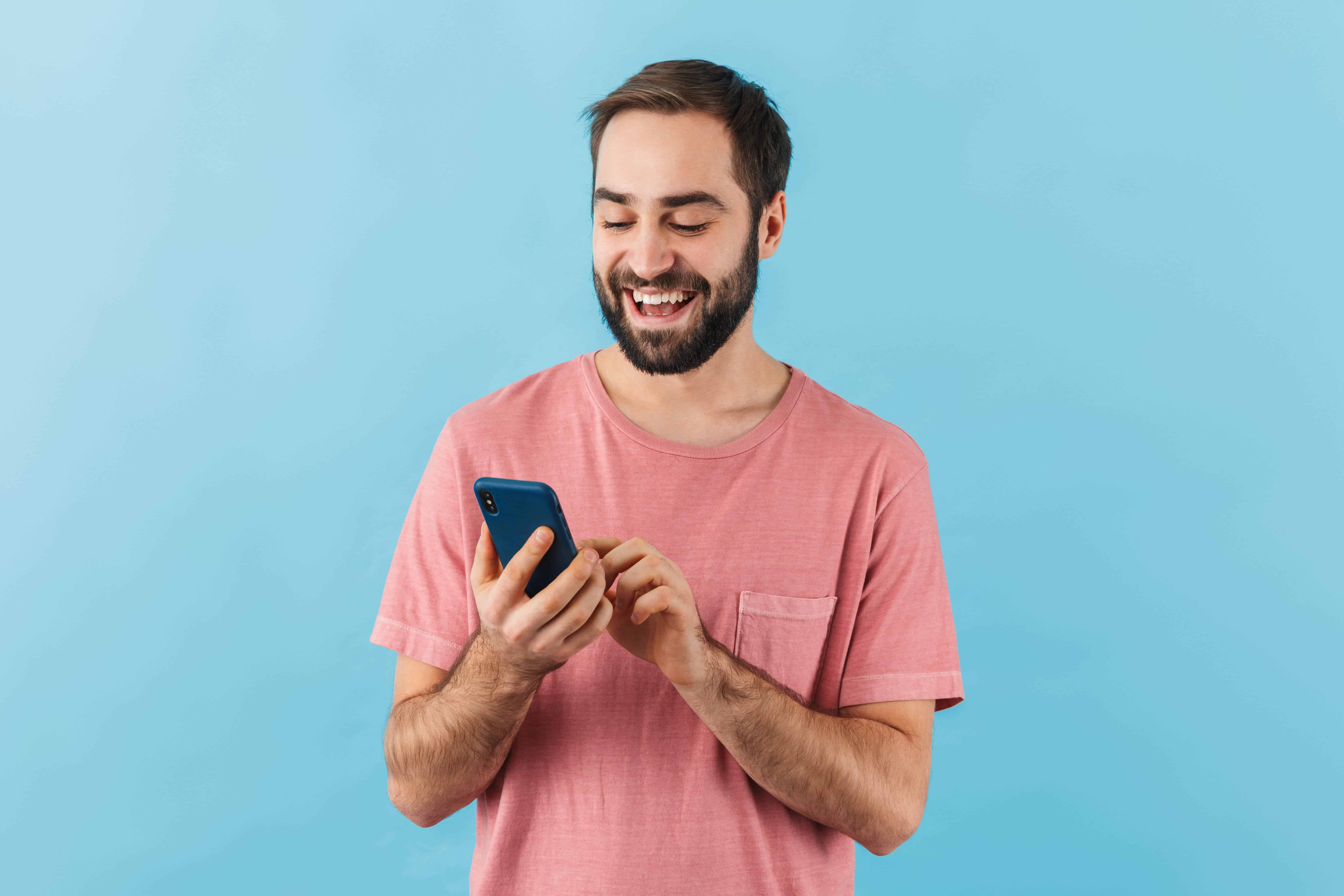 Smiling man in a pink shirt enjoys his customer journey on a smartphone.