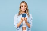 Smiling woman in blue shirt holding a smartphone, reflecting mobile-first design.