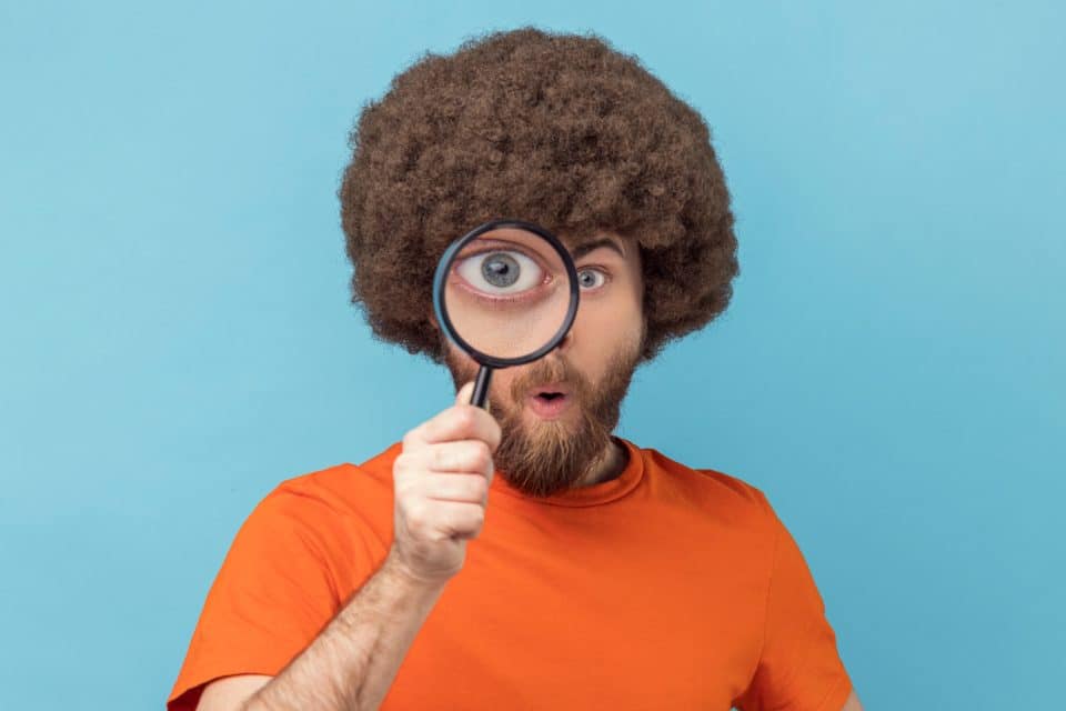 Person examining backlinks with magnified eye against blue background.
