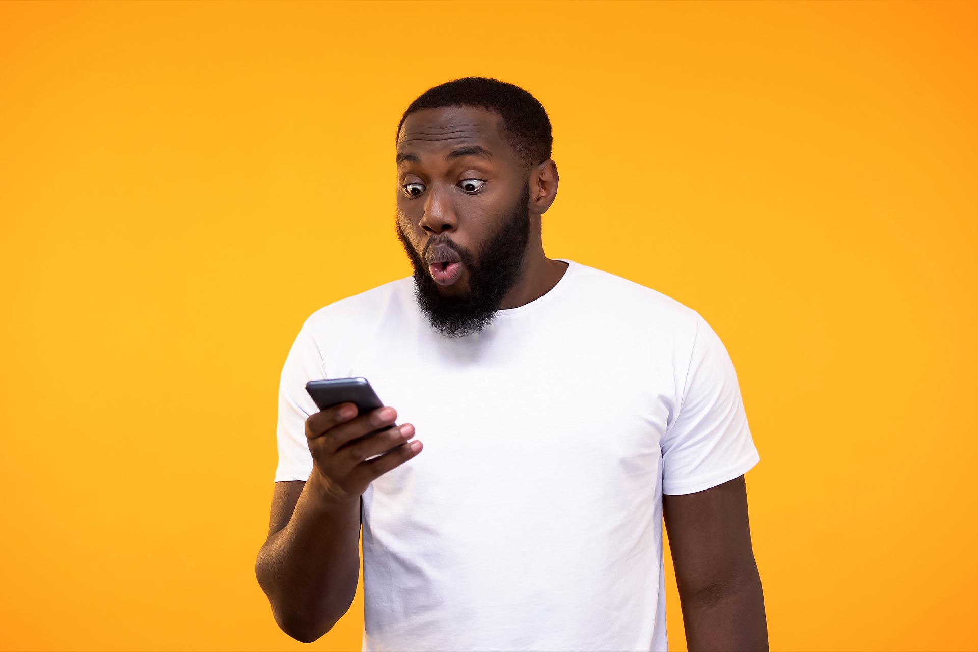 Man in white t-shirt looks surprised while reading a landing page on his phone.